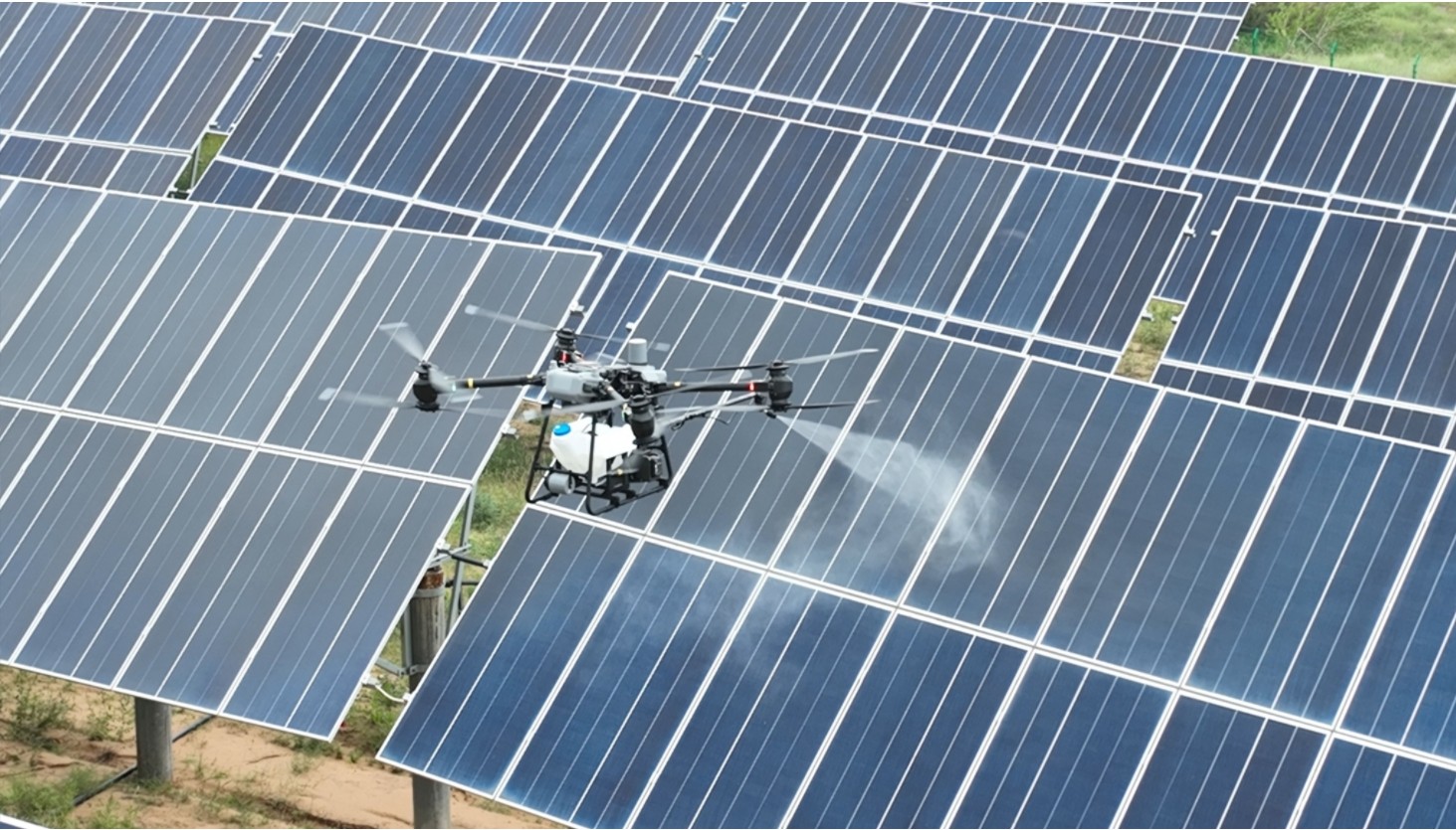 Cleaning drone spraying a utility-scale solar array