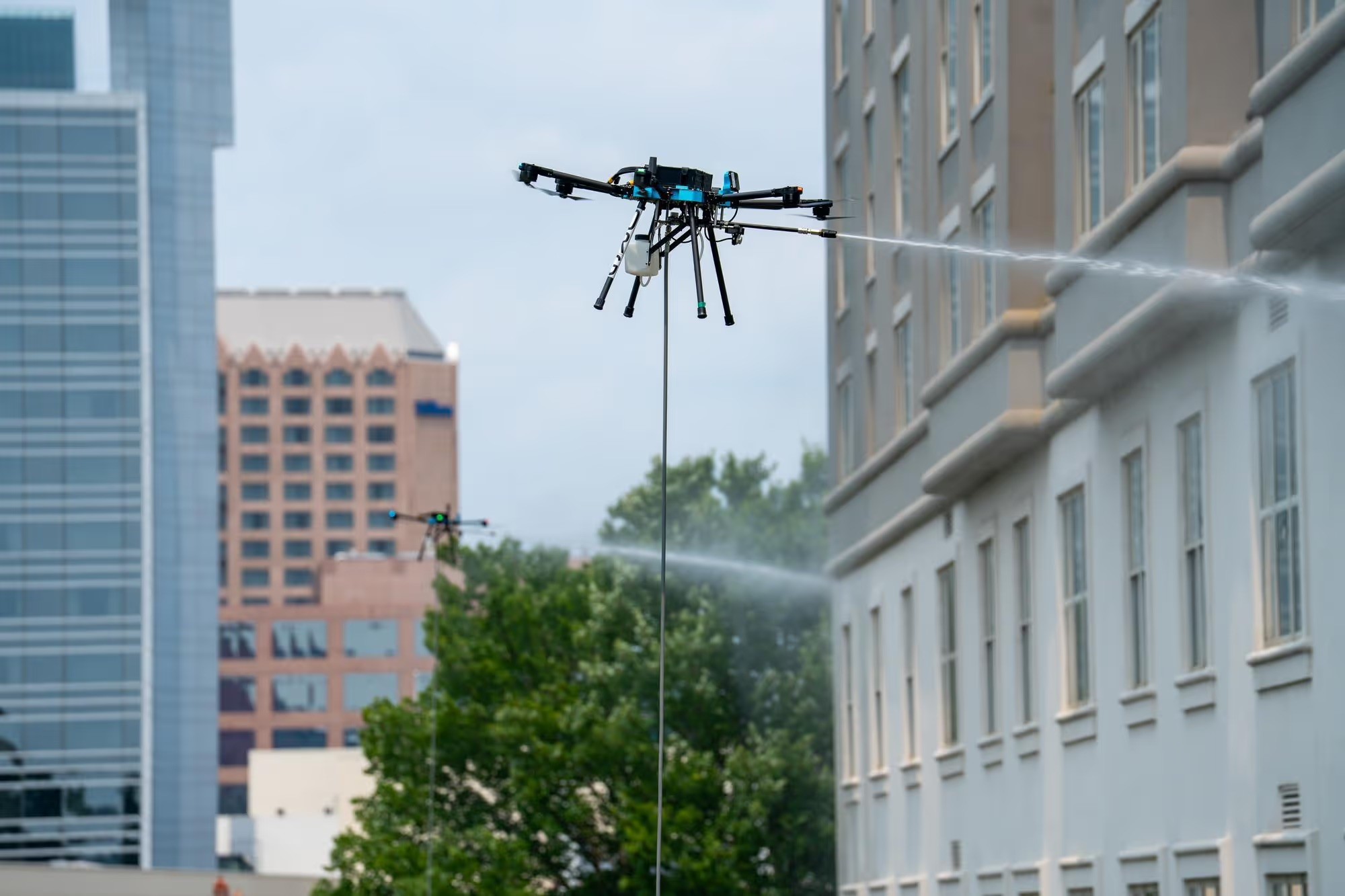 Cleaning drones spraying a commercial building facade